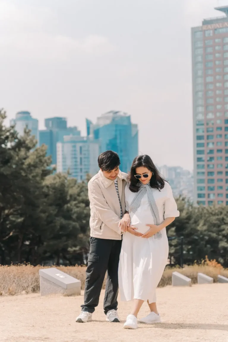 Expecting couple looking down at the baby bump during an outdoor maternity photoshoot in Seoul