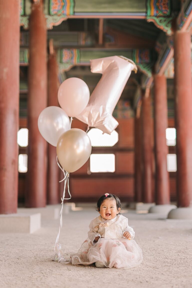 Baby celebrating a first birthday with balloons at a traditional Korean location in Seoul