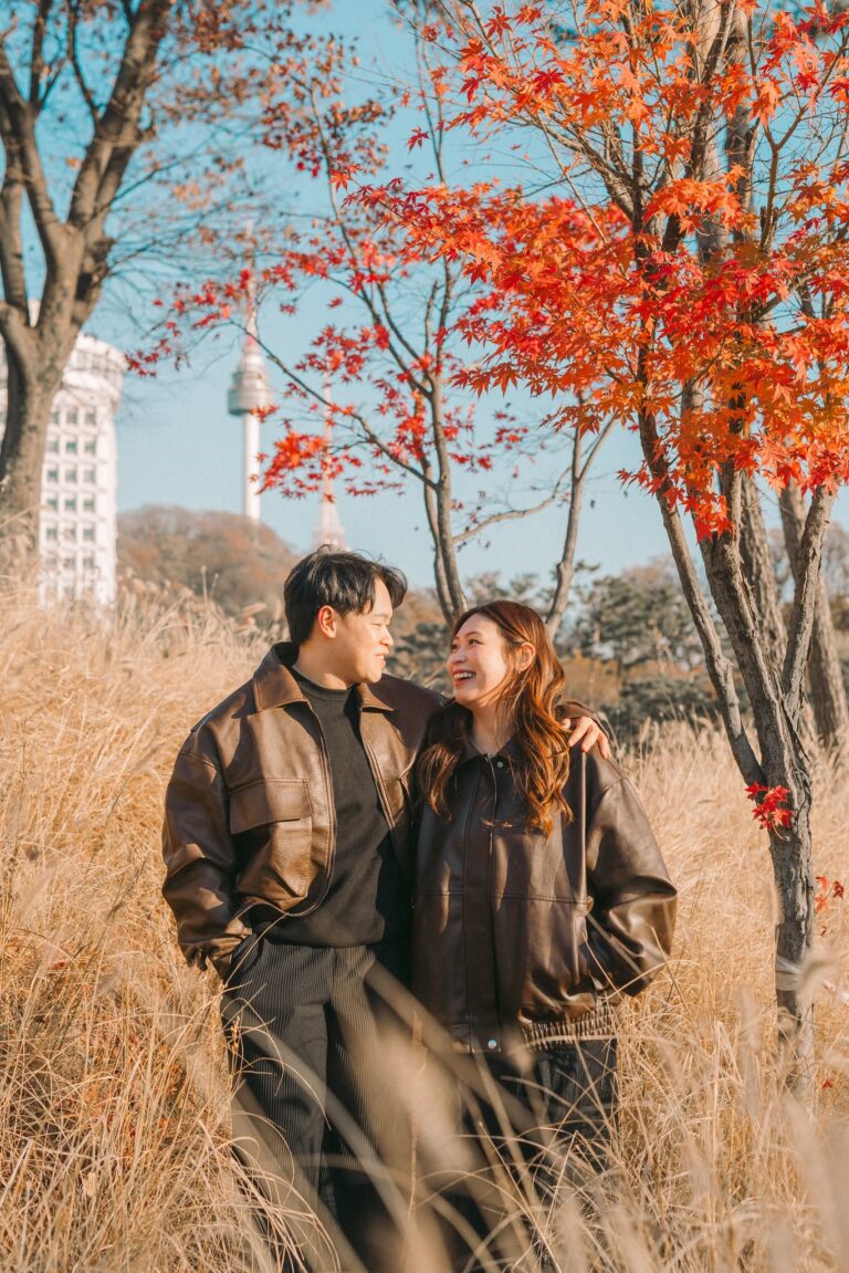 Couple laughing together beneath autumn leaves in Seoul