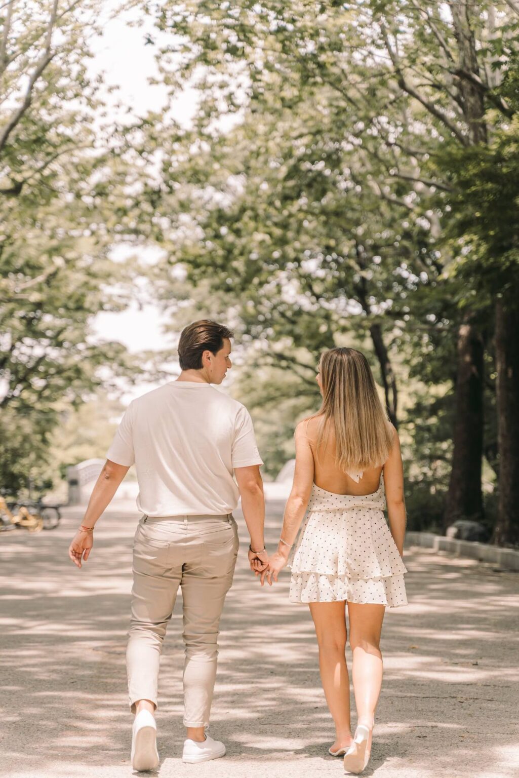 Couple walking hand in hand beneath trees during a Seoul photography session