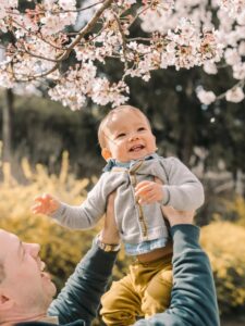 Parent lifting a smiling baby during an outdoor family photoshoot in Seoul