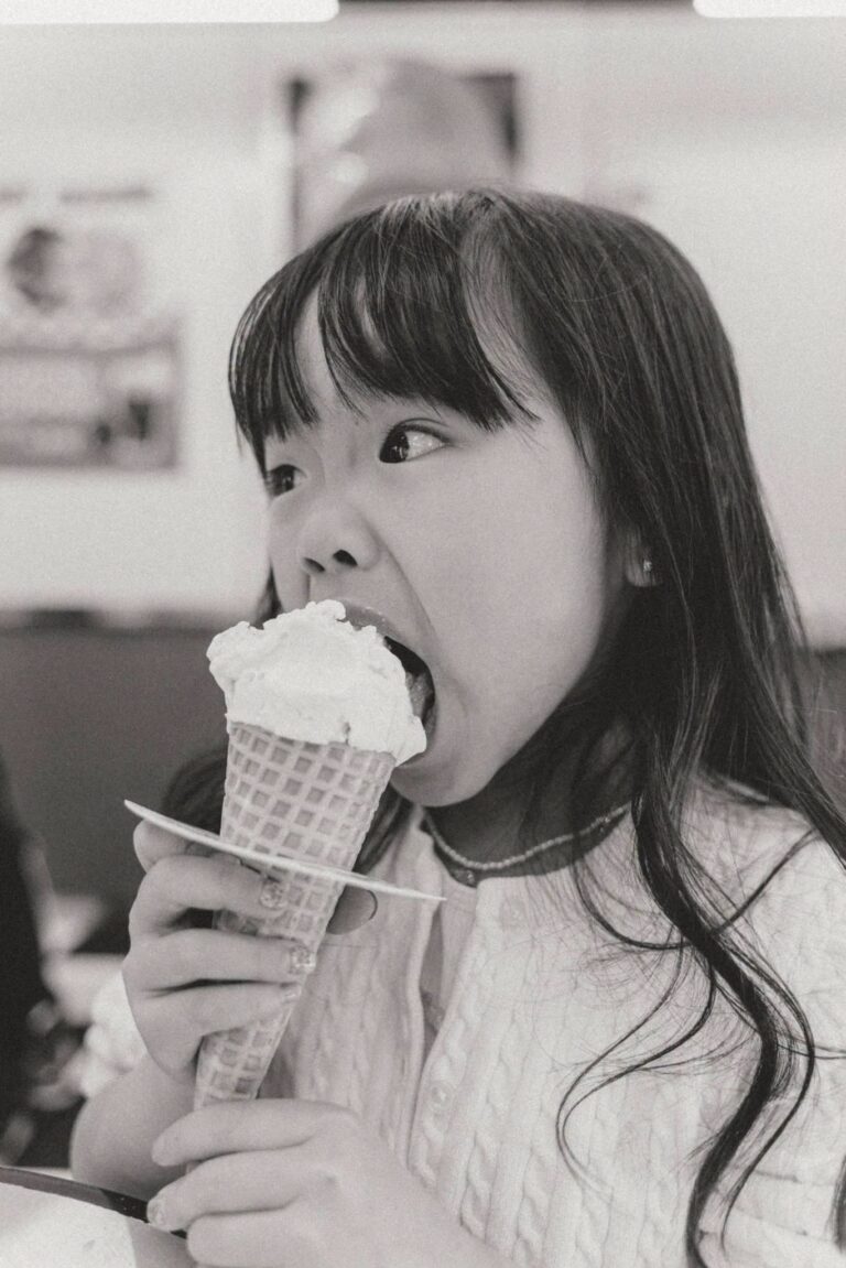 Black and white candid portrait of a young girl eating an ice cream cone