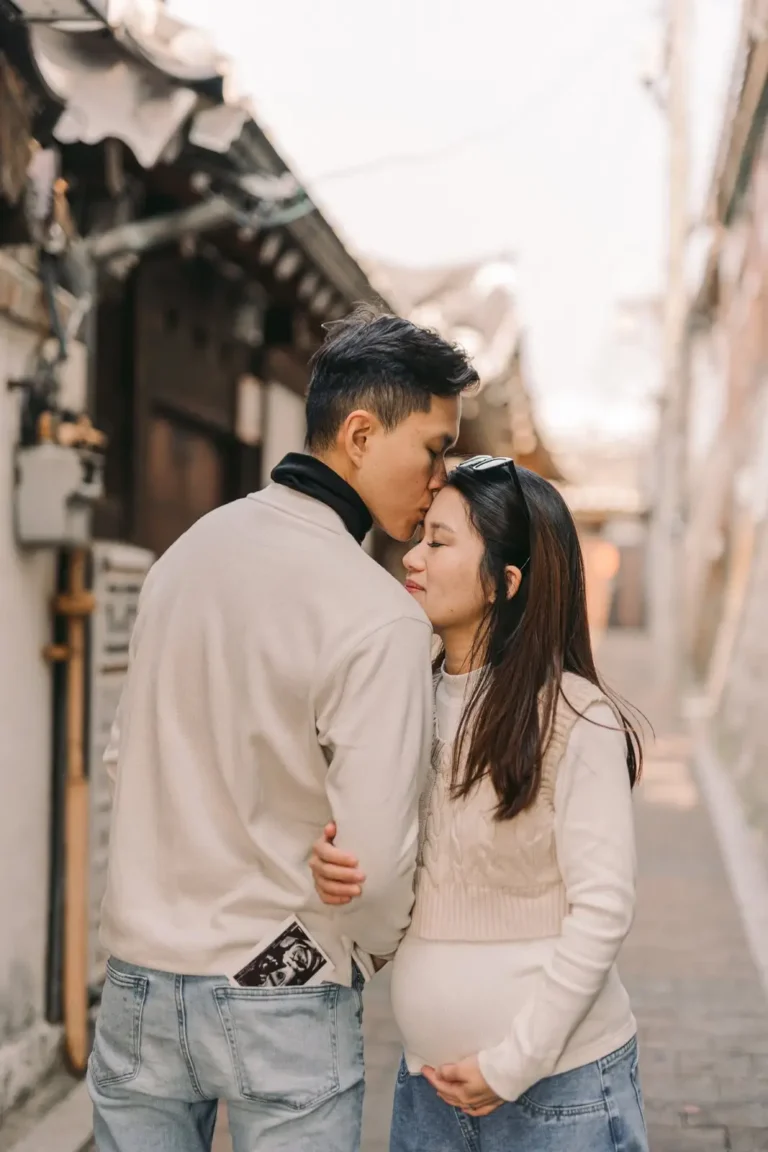 Expecting couple embracing during a maternity session in a traditional Seoul alley