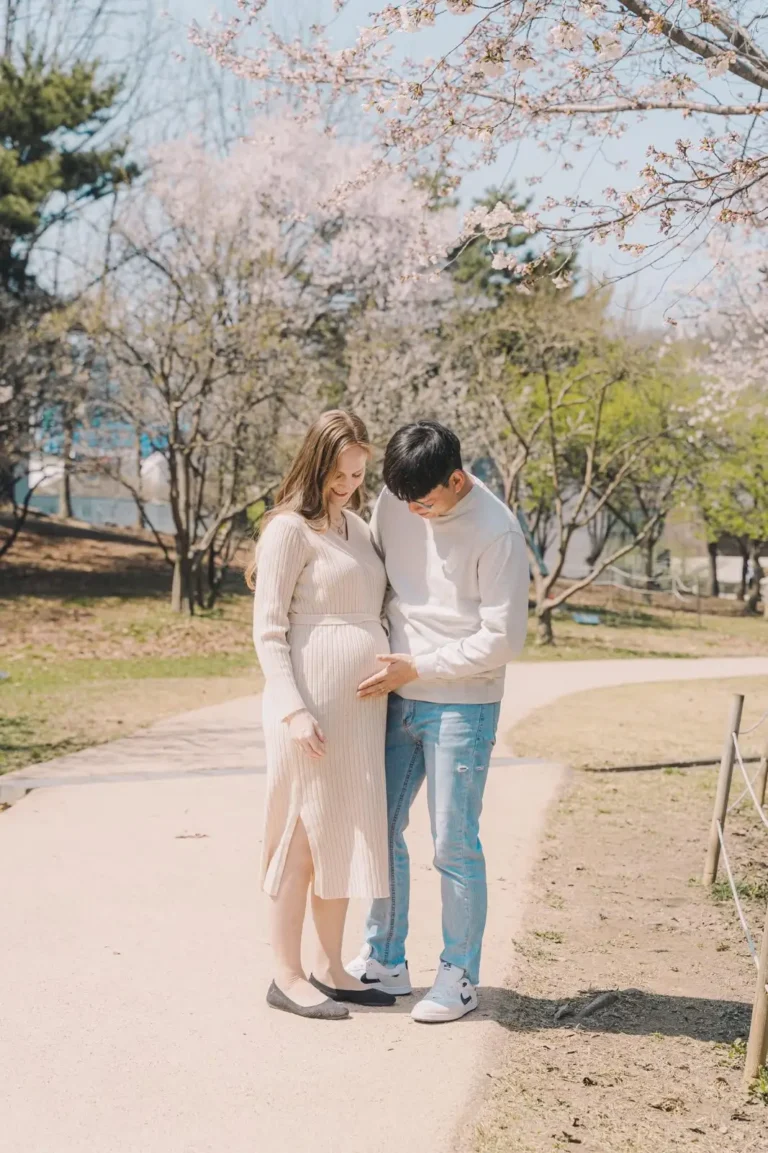 Expecting couple walking together outdoors while looking at the baby bump
