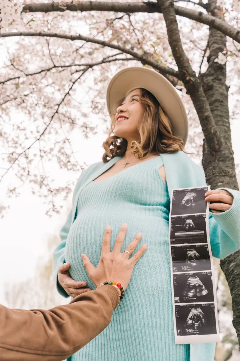 Pregnant woman holding ultrasound photos beneath cherry blossoms in Seoul