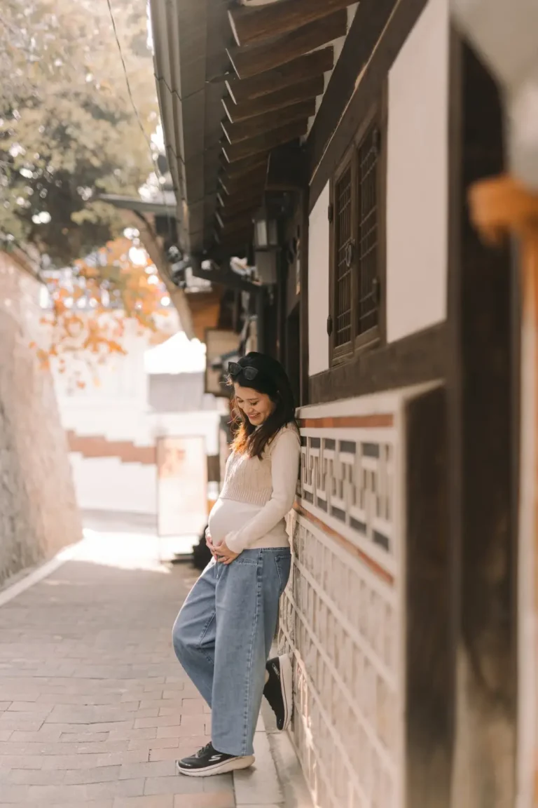 Pregnant woman standing beside a traditional hanok wall during a maternity photoshoot in Seoul