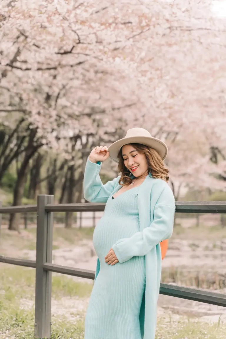Expecting mother posing beneath blooming cherry trees during a Seoul maternity photoshoot