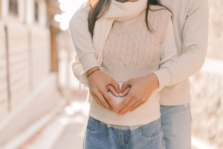 Expecting parents forming a heart with their hands over the baby bump
