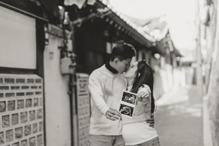 Black and white portrait of an expecting couple holding ultrasound photos in Seoul