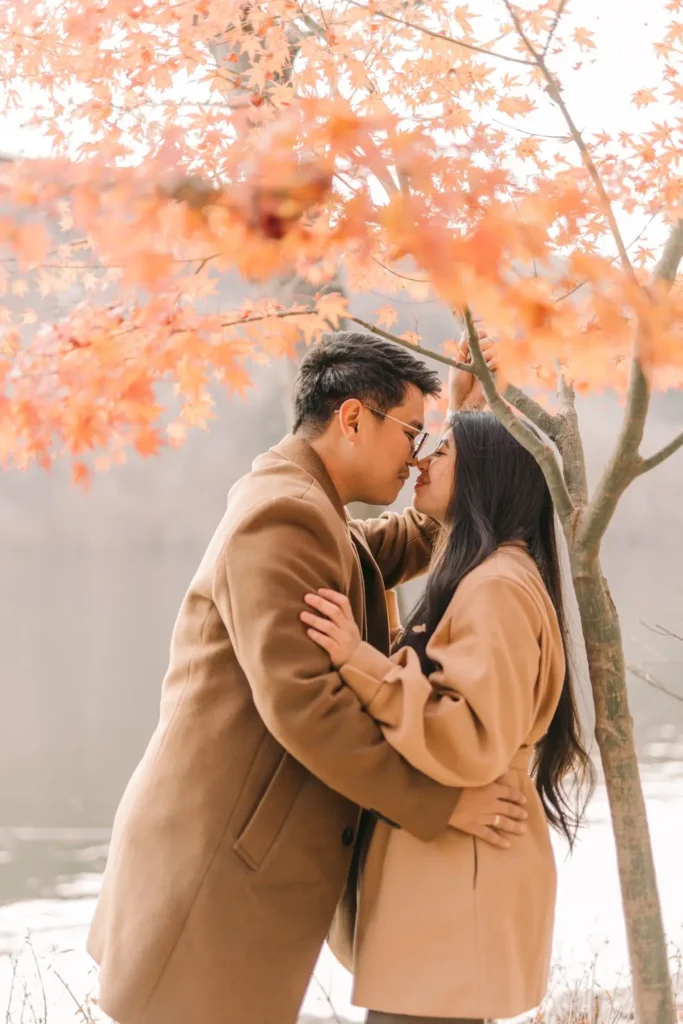 Engaged couple embracing beneath autumn trees at nami island