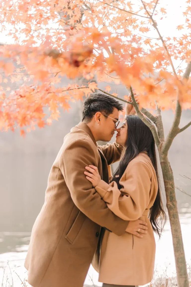 Engaged couple embracing beneath autumn trees at nami island