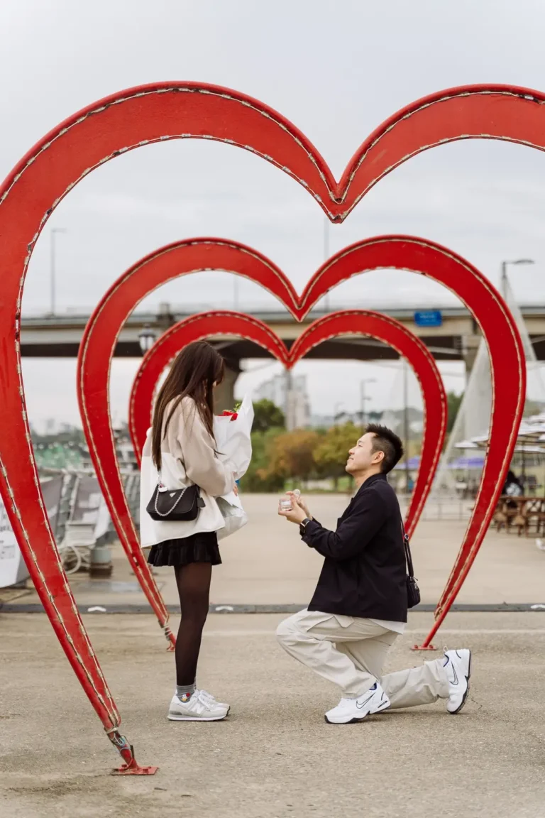 Partner proposing beneath heart sculptures during a romantic Seoul photoshoot