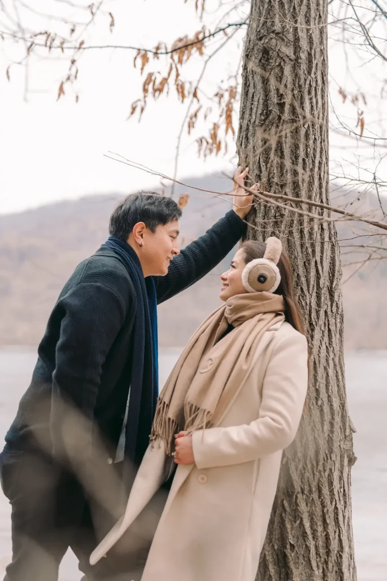 Couple sharing a playful moment beside a tree during winter in Korea