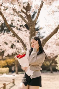 Newly engaged woman holding roses beneath cherry blossoms in nami island