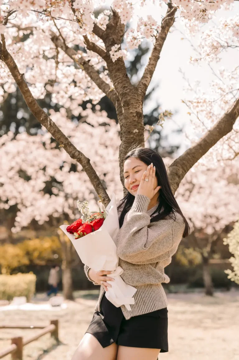 Newly engaged woman holding roses beneath cherry blossoms in nami island