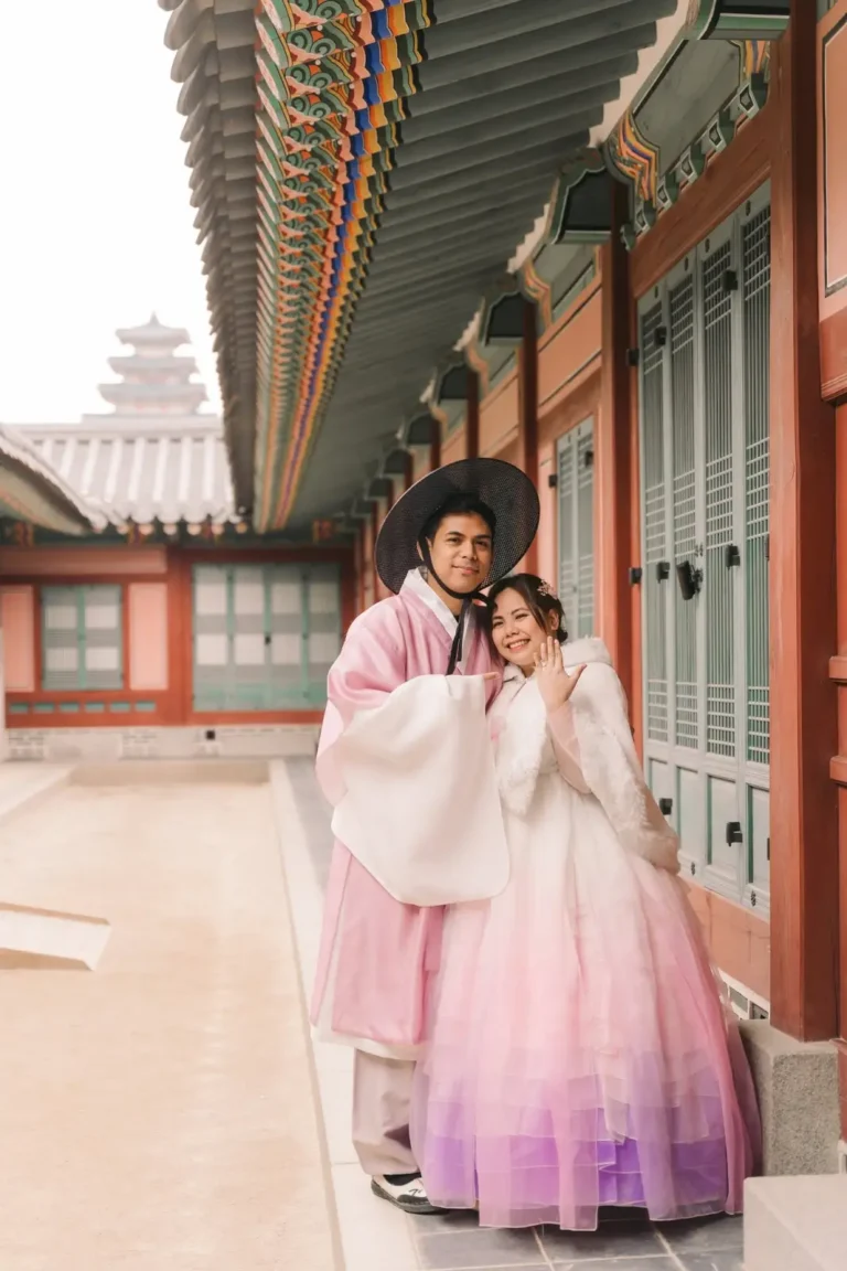 Engaged couple wearing pink hanbok during a photoshoot at a Seoul palace