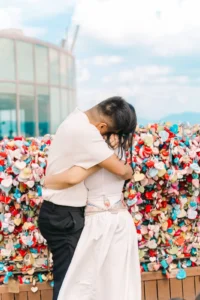 Couple embracing beside colorful love locks during their Seoul photography session