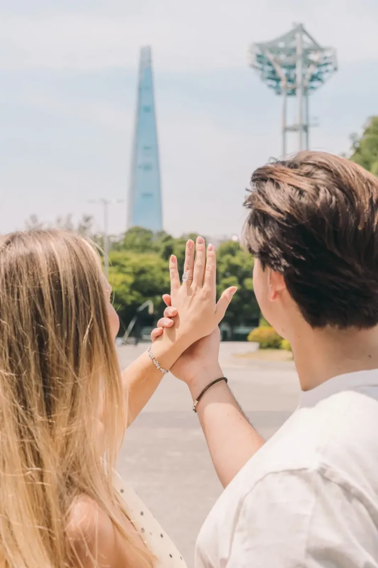 Couple showing an engagement ring with the Seoul skyline in the background
