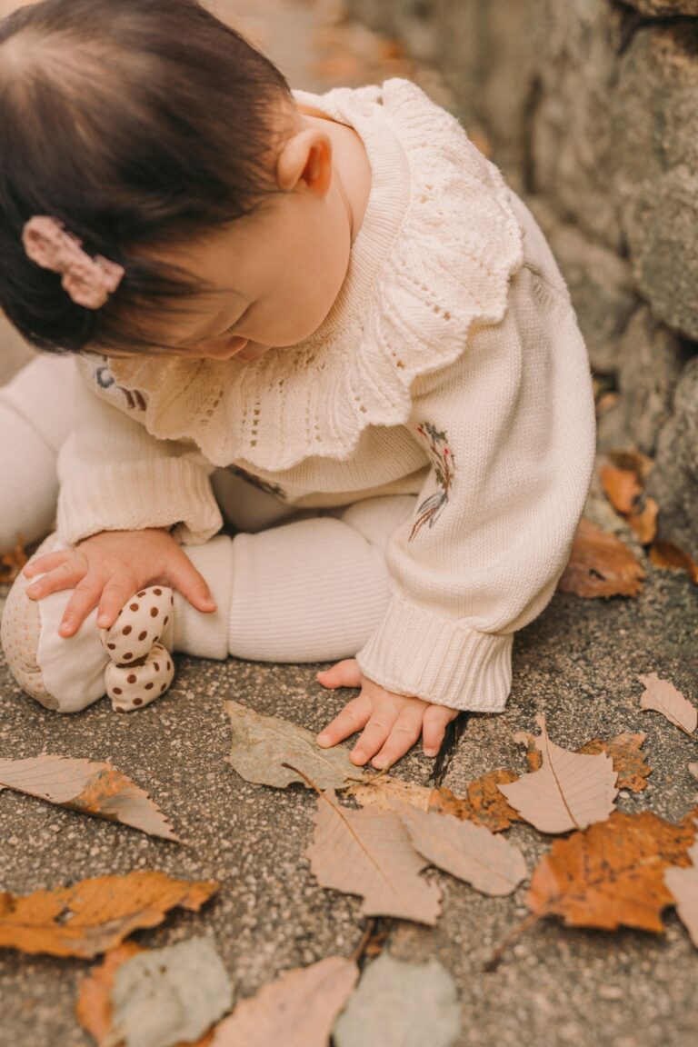 Young child exploring fallen autumn leaves during a seasonal family photoshoot in Seoul