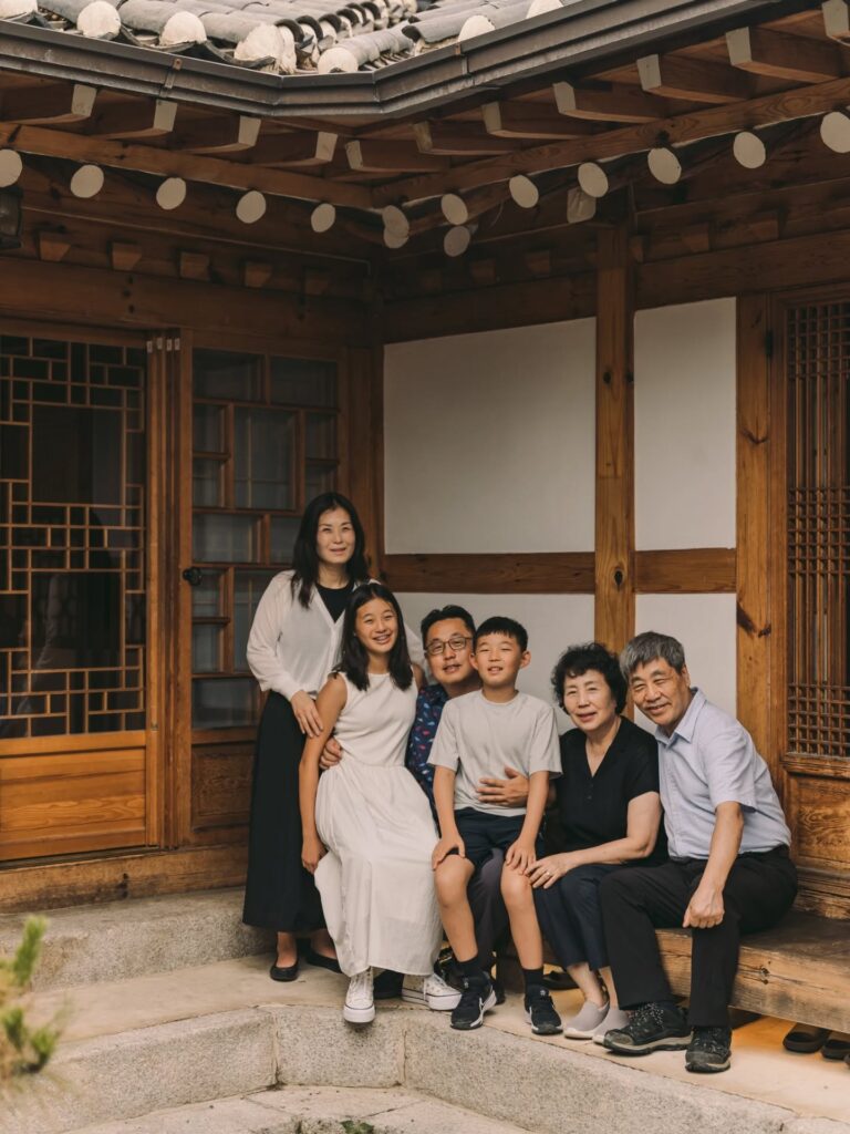 Multigenerational family posing together outside a traditional Korean hanok