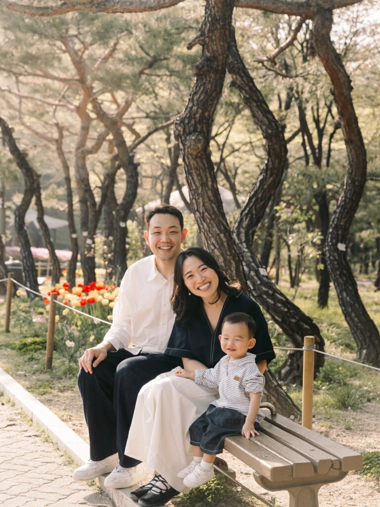 Parents and their young child sitting together in a sunny Seoul garden