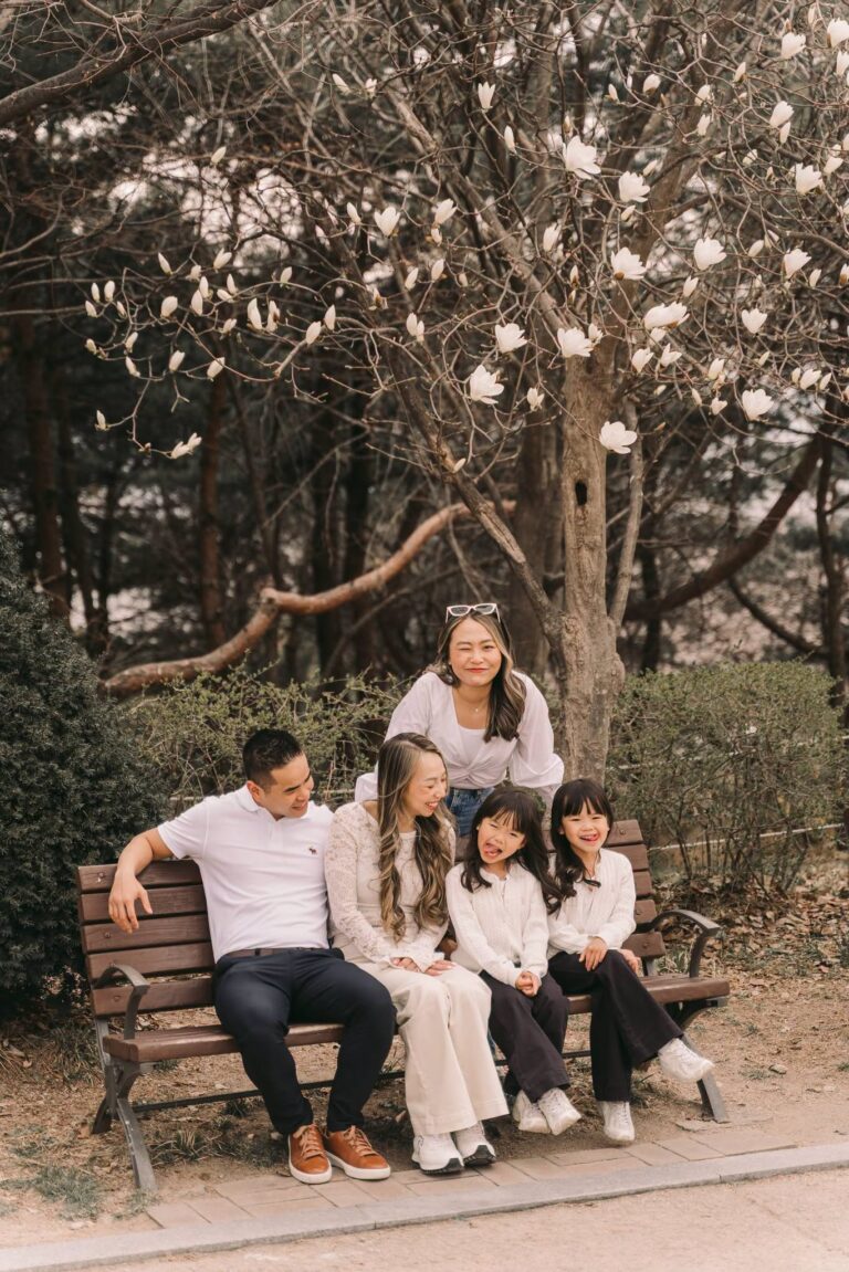 Parents and children relaxing together on a park bench during a candid Seoul family session