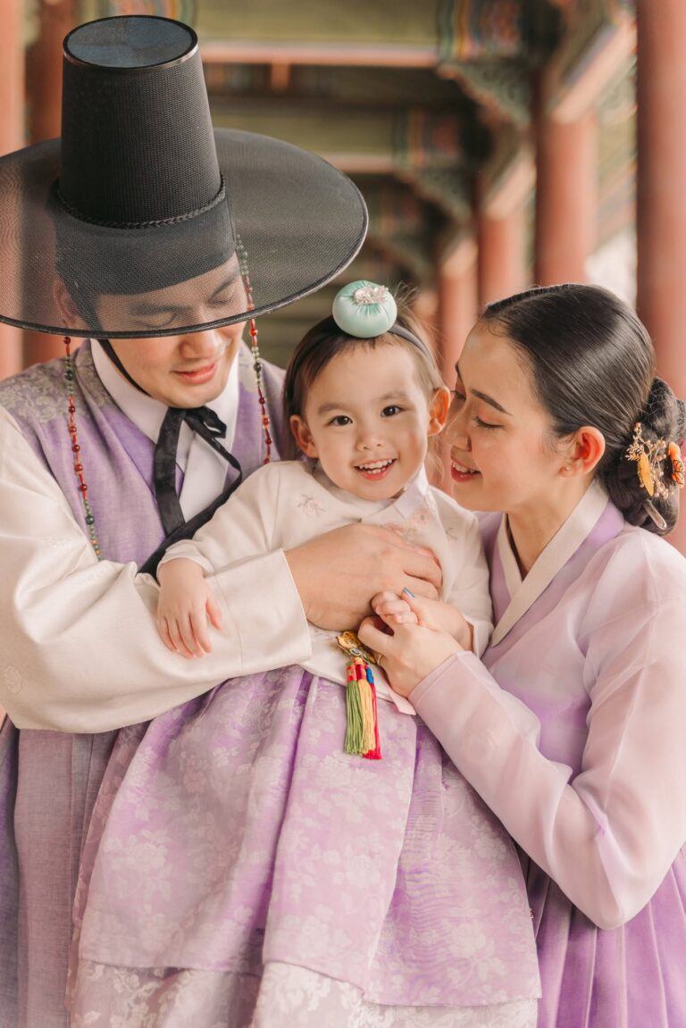 Parents wearing traditional Korean hanbok and smiling with their baby during a Seoul photoshoot