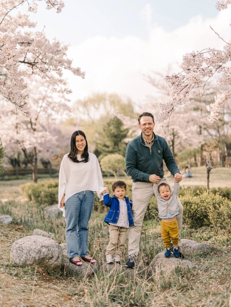 Parents walking with their two children beneath cherry blossoms during spring in Seoul