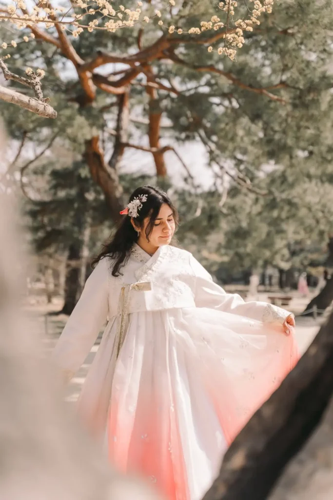 Woman showing the flowing skirt of her white and pink hanbok during a Seoul photoshoot