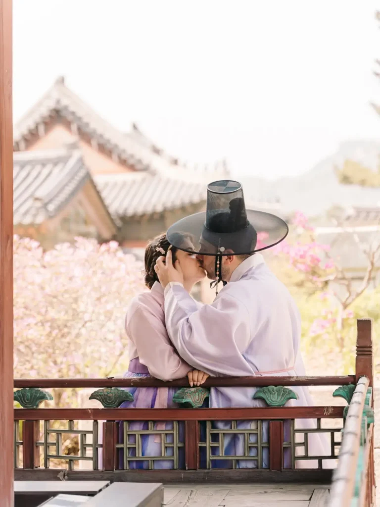 Couple kissing while wearing pastel traditional hanbok at Gyeongbokgung Palace