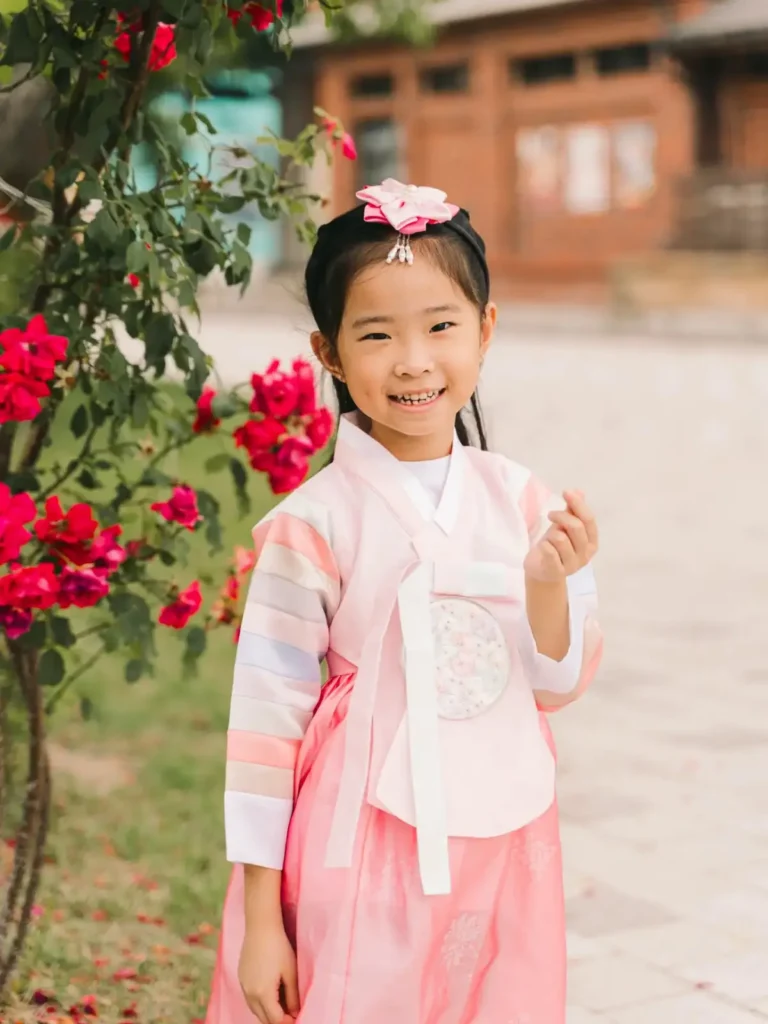 Young girl wearing a pink traditional Korean hanbok beside flowers at Gyeongbokgung Palace