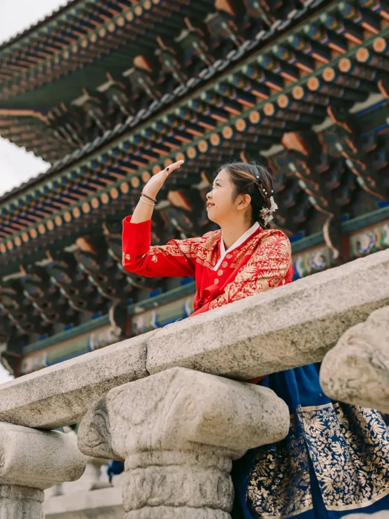 Woman wearing red and blue traditional Korean hanbok beneath Gyeongbokgung Palace architecture