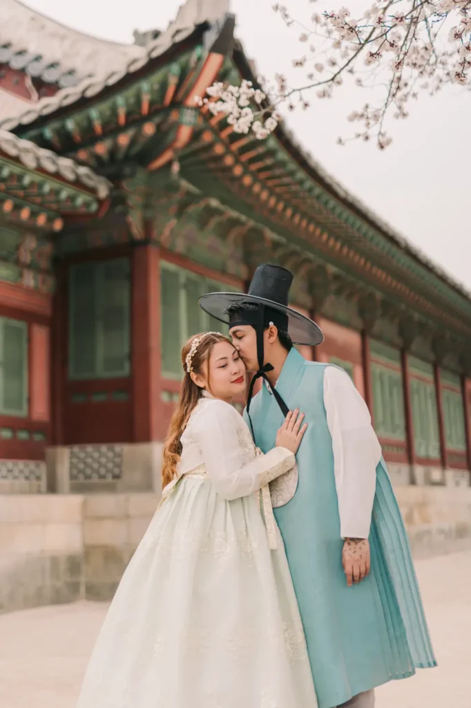 Couple wearing traditional Korean hanbok sharing a quiet moment beside the palace