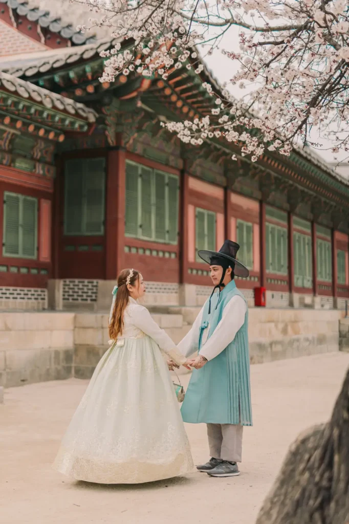 Couple holding hands in traditional Korean hanbok at Gyeongbokgung Palace in Seoul