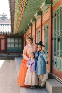 Mother and two children wearing colorful traditional hanbok beside the palace buildings