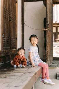 Two children sitting together at a traditional Korean house during a kids photoshoot in Seoul.