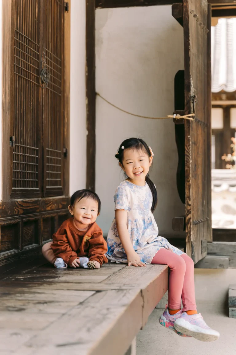 Two children sitting together at a traditional Korean house during a kids photoshoot in Seoul.