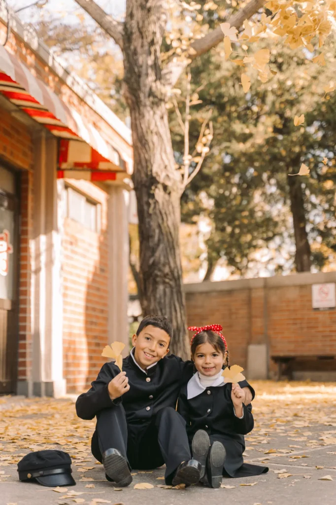 kids throwing ginko tree leaves in seoul in old korean school uniform